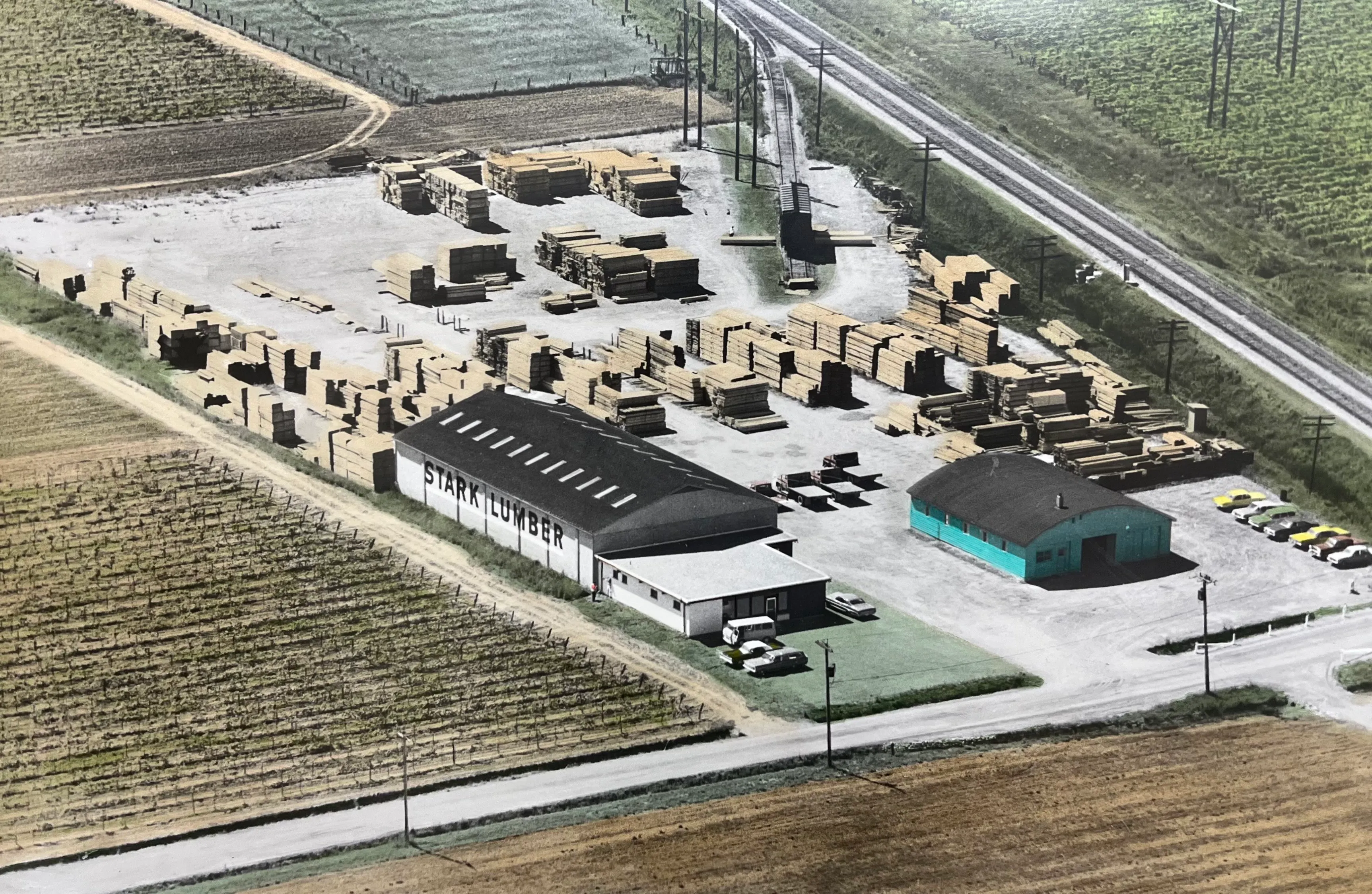 Aerial photograph of the Stark Lumber yard on Vansickle Rd., surrounded by vineyards, with STARK LUMBER painted on the warehouse roof